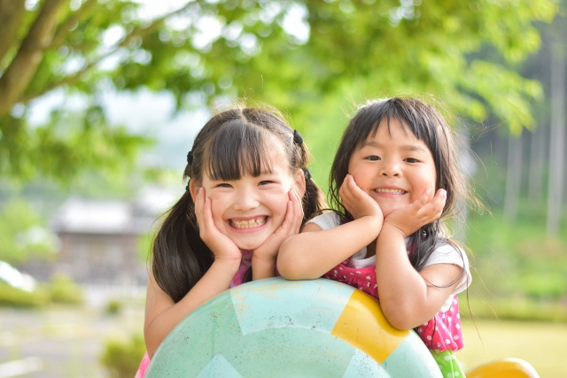 遊具に頬杖をついて笑っている二人の少女
